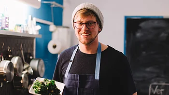 Koch in der Küche mit Grünkohl