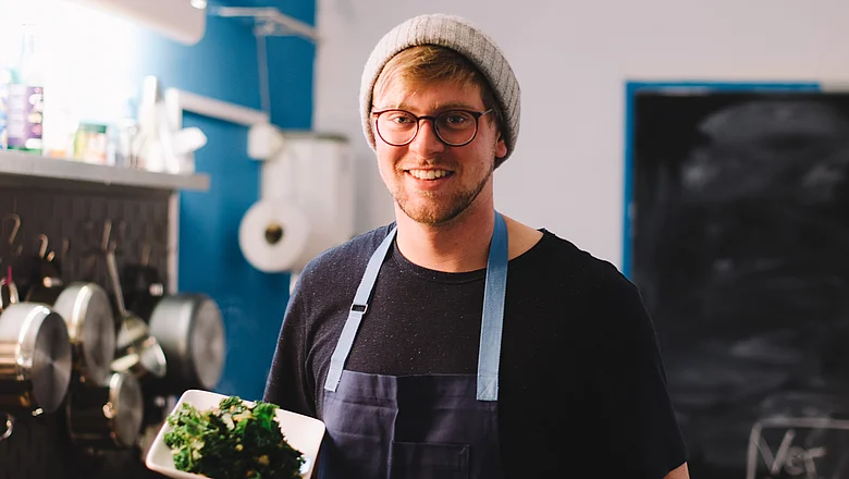 Koch in der Küche mit Grünkohl 