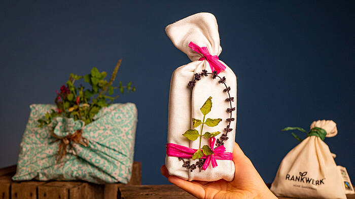 Geschenke sind in Stoff eingepackt und mit Blüten und Zweigen schön dekoriert