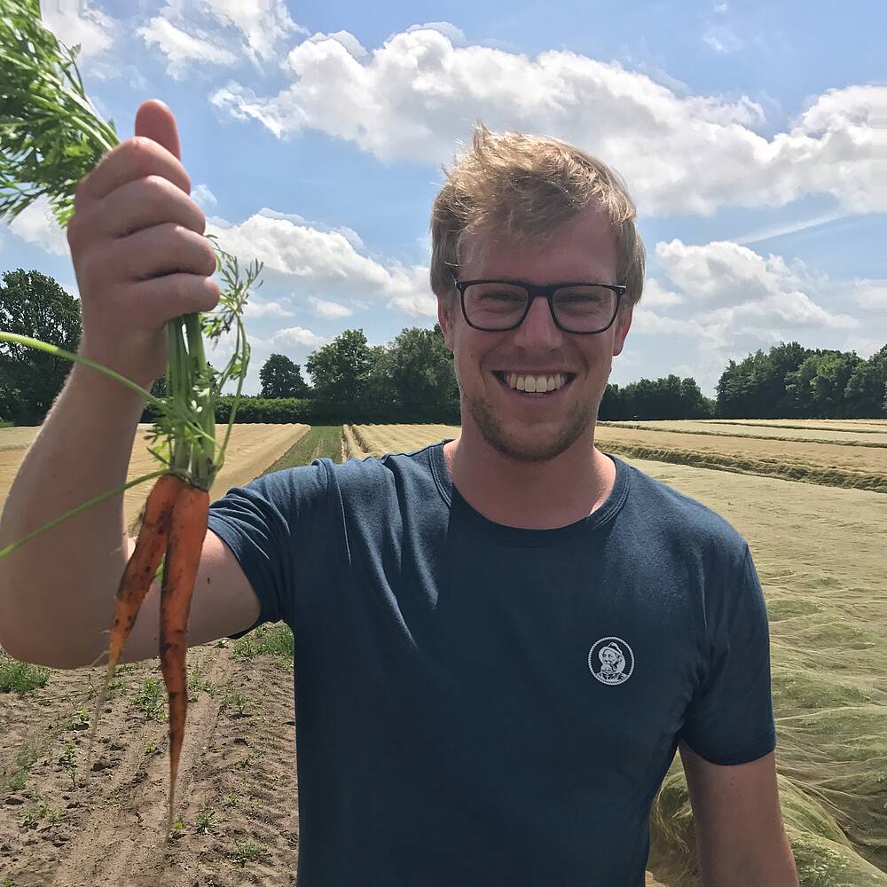 Glücklicher Mann mit Karotten in der Hand